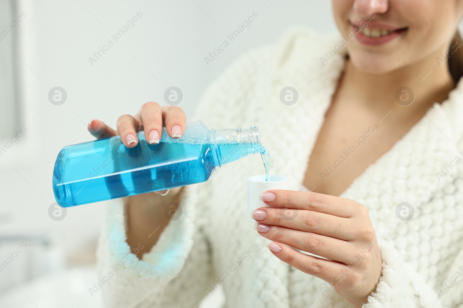 Photo of Young woman using mouthwash indoors, closeup view