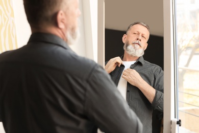 Photo of Mature man looking in mirror at home