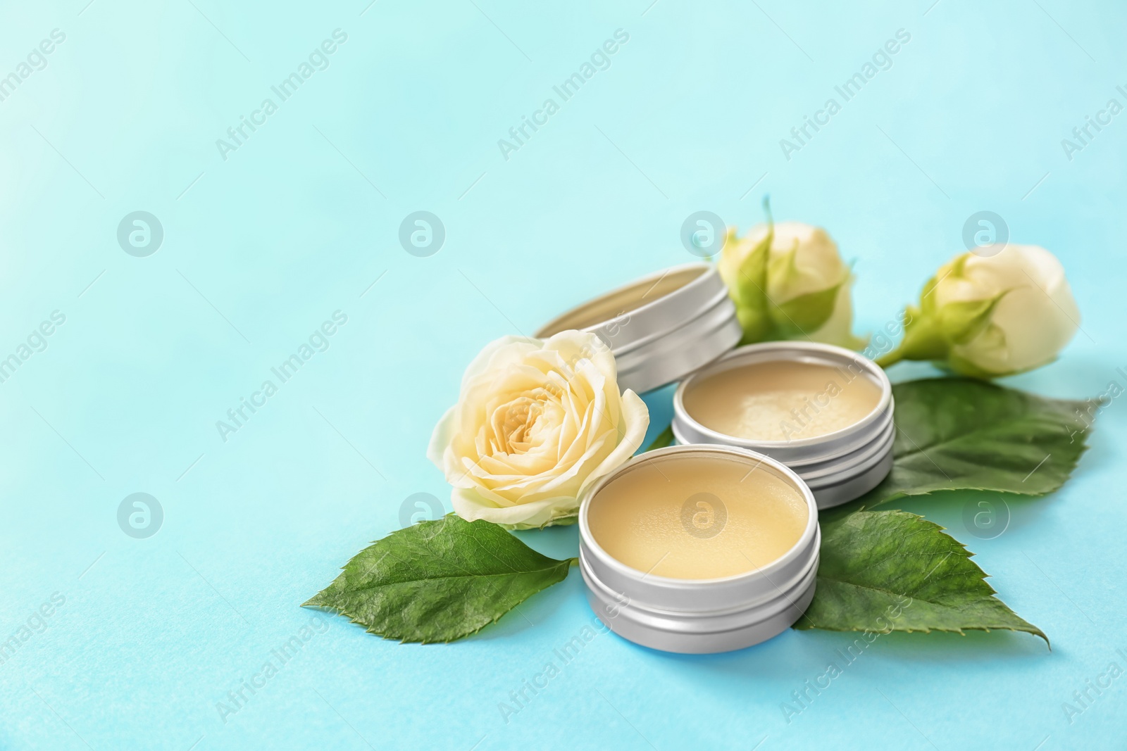 Photo of Hygienic lip balms and flowers on color background