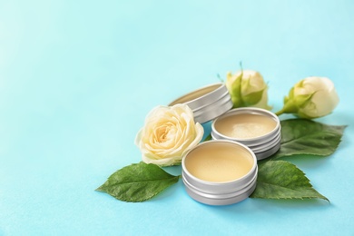 Hygienic lip balms and flowers on color background