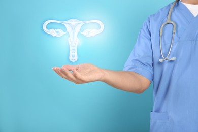 Doctor and illustration of female reproductive system on light blue background, closeup