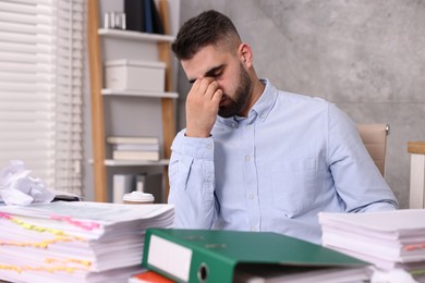 Overwhelmed man surrounded by documents at workplace in office