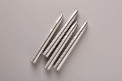 Photo of Many metal bullets on light grey background, flat lay