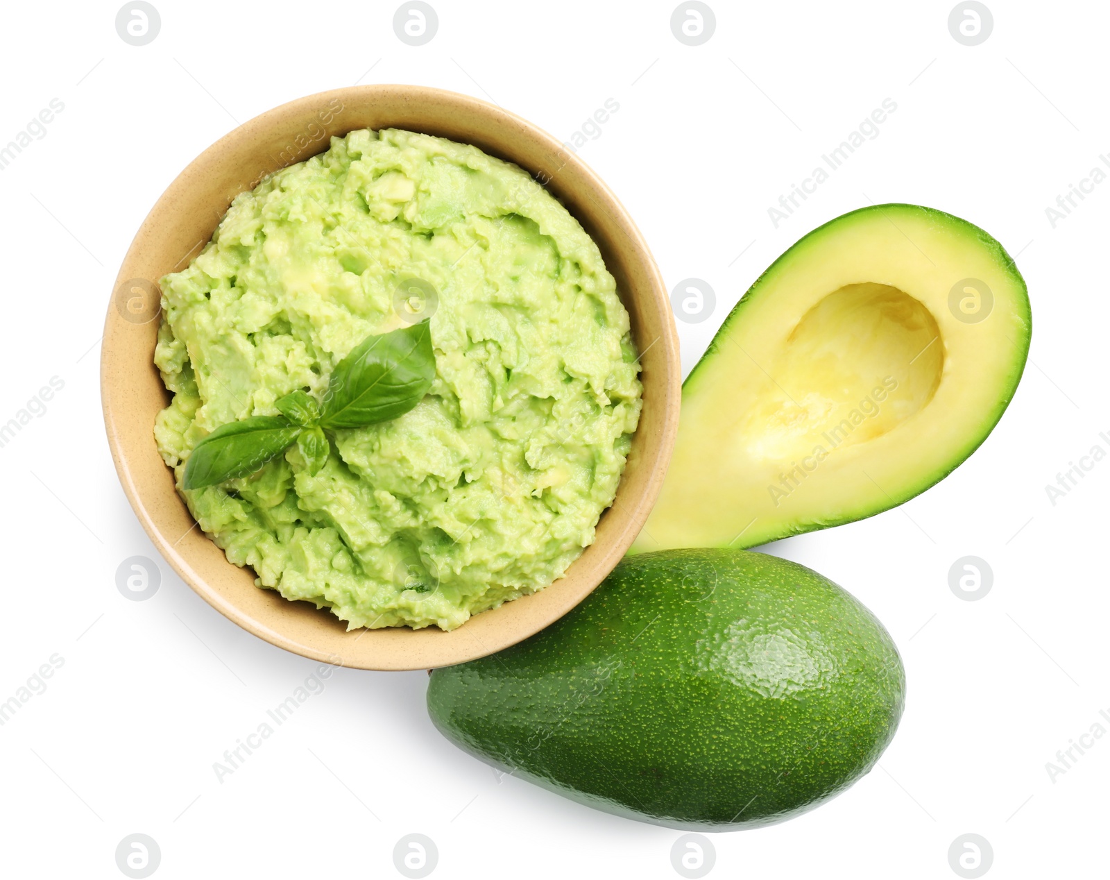 Photo of Bowl of tasty guacamole with basil and avocados on white background, top view