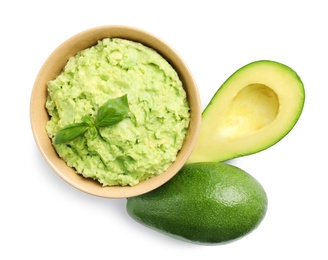 Bowl of tasty guacamole with basil and avocados on white background, top view