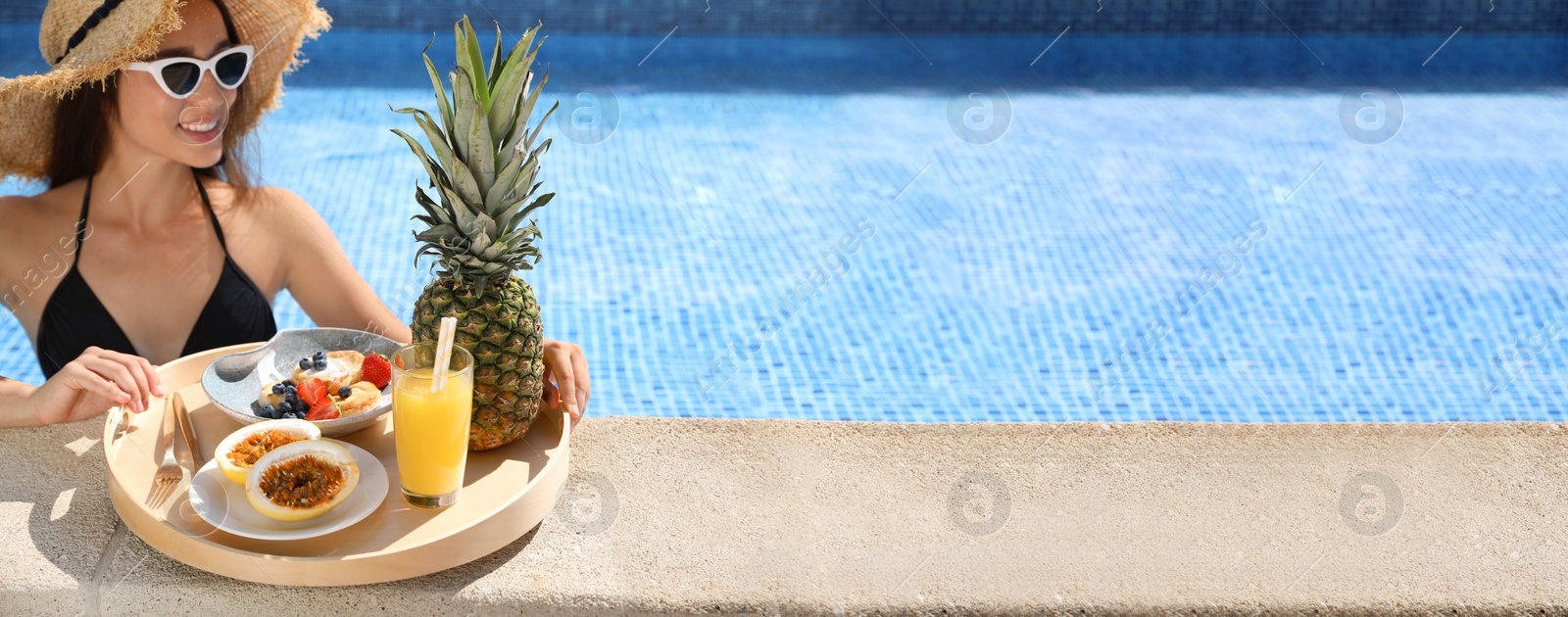 Photo of Young woman with delicious breakfast on tray in swimming pool. Space for text