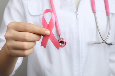 Doctor holding pink ribbon, closeup. Breast cancer awareness