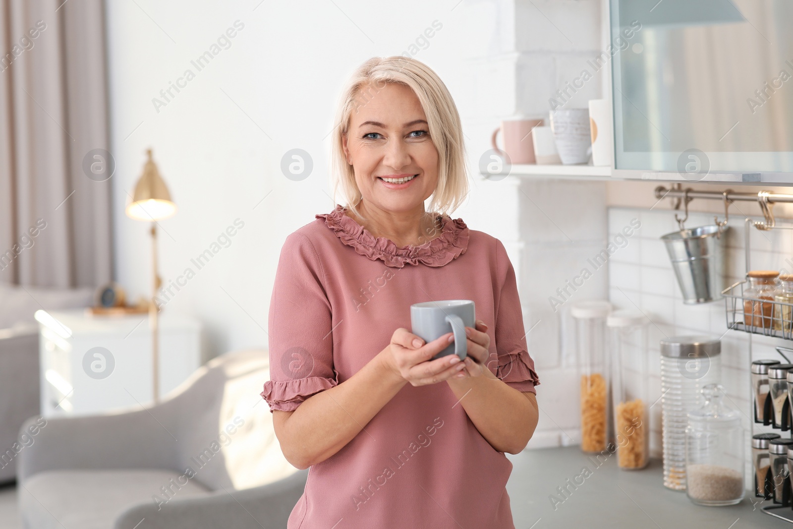 Photo of Portrait of beautiful mature woman with cup in kitchen