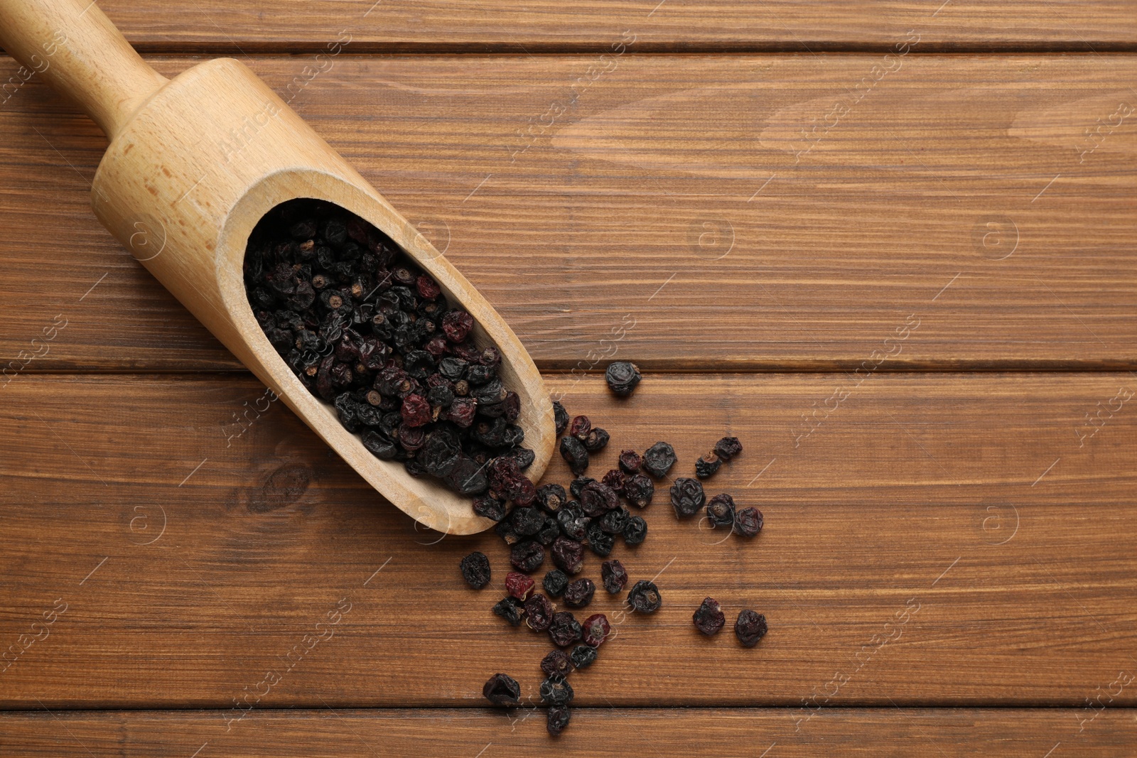 Photo of Dried black currants and scoop on wooden table, flat lay. Space for text