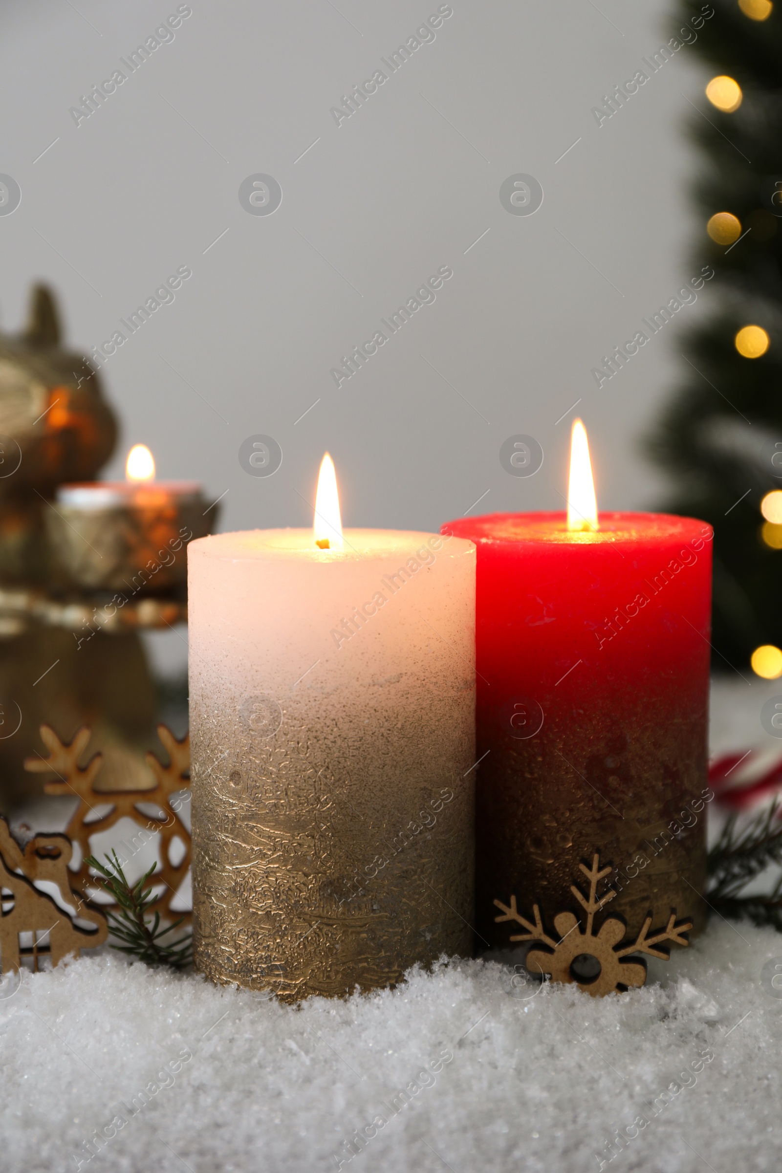 Photo of Burning candles and Christmas decor on artificial snow