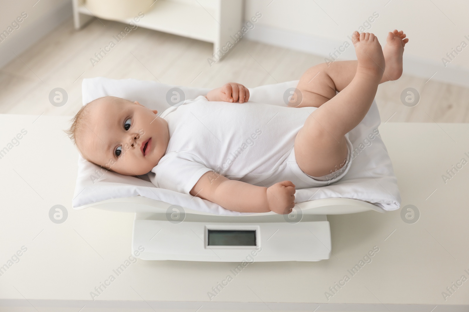 Photo of Cute little baby lying on scales in clinic