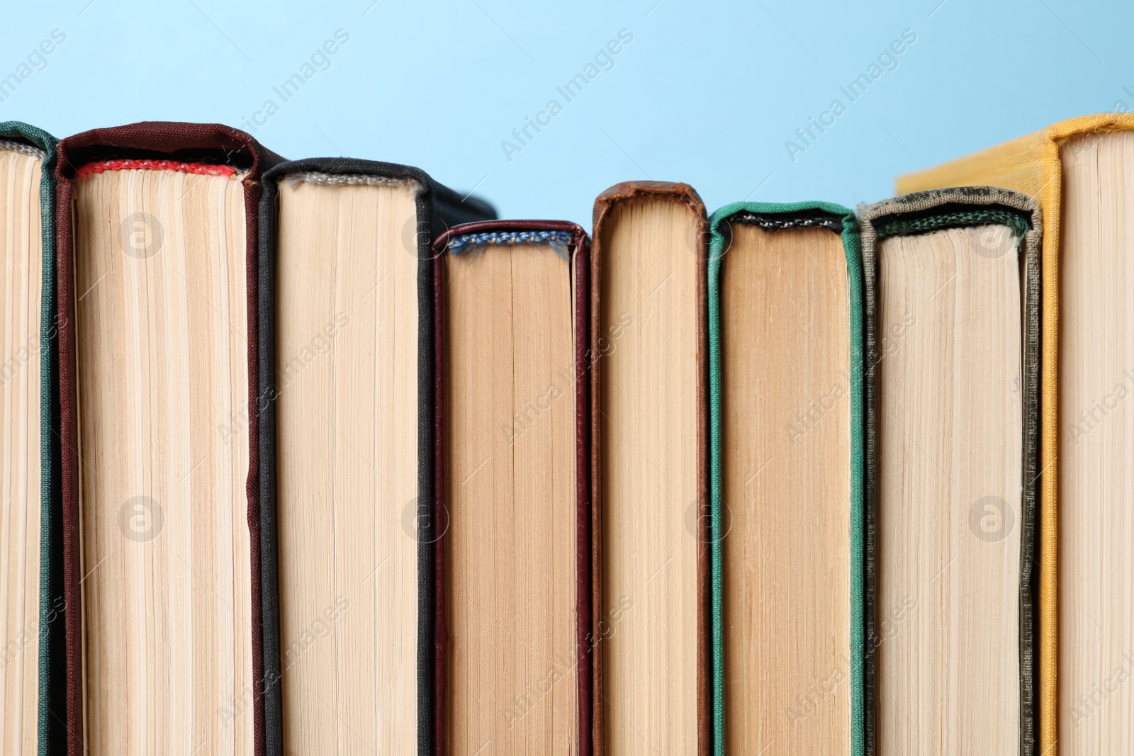 Photo of Many old books on light blue background, closeup