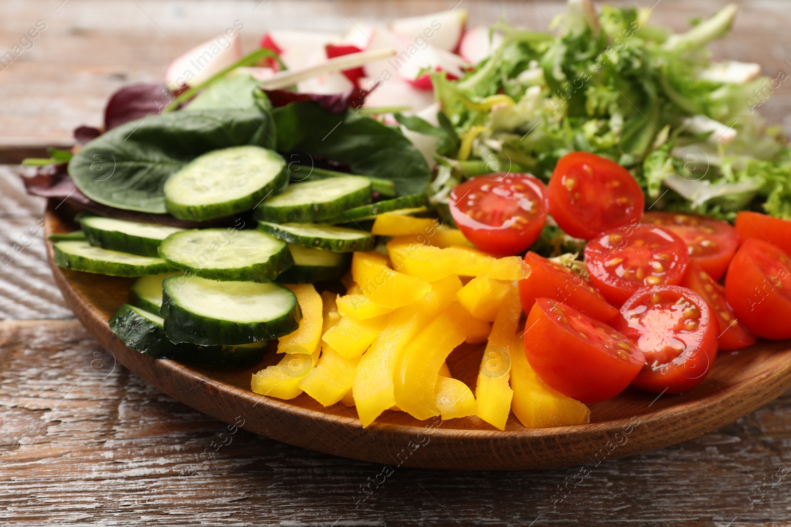 Photo of Vegetarian diet. Plate with tasty vegetables on wooden table, closeup