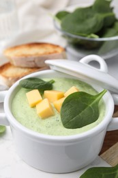 Delicious spinach cream soup with cheese in bowl on light grey table