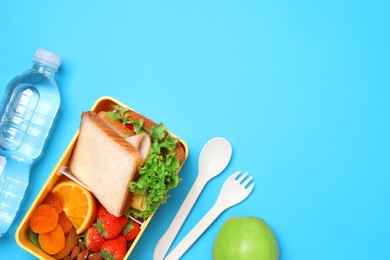 Flat lay composition with tasty food, water and cutlery on light blue background, space for text. School dinner