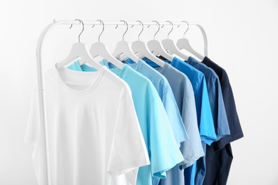 Photo of Men's clothes hanging on wardrobe rack against white background