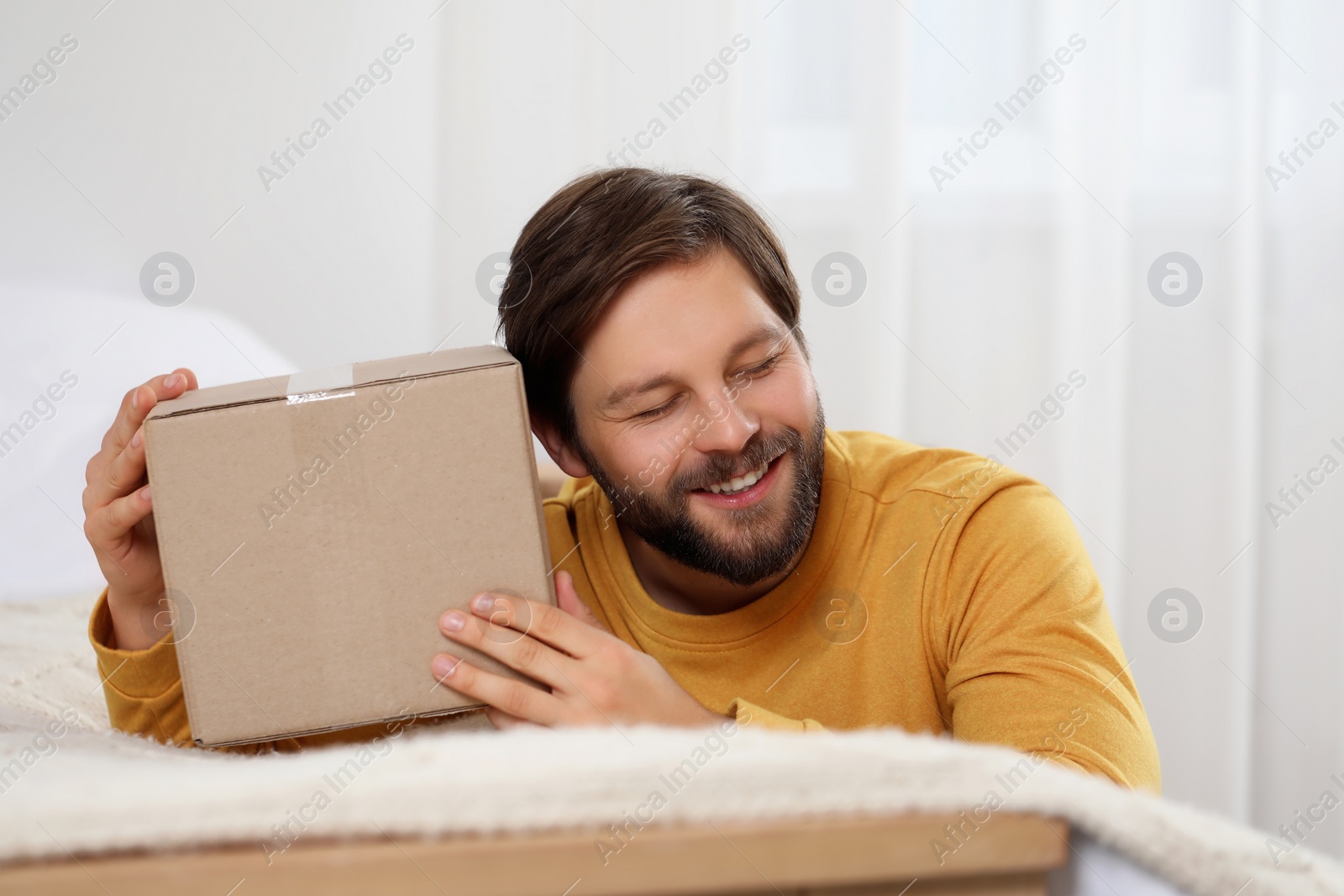 Photo of Happy man with parcel at home. Internet shopping