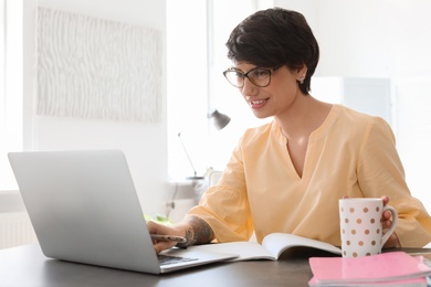 Photo of Young woman working with laptop at desk. Home office