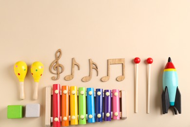 Photo of Baby song concept. Wooden notes, kids xylophone and toys on beige background, flat lay. Space for text