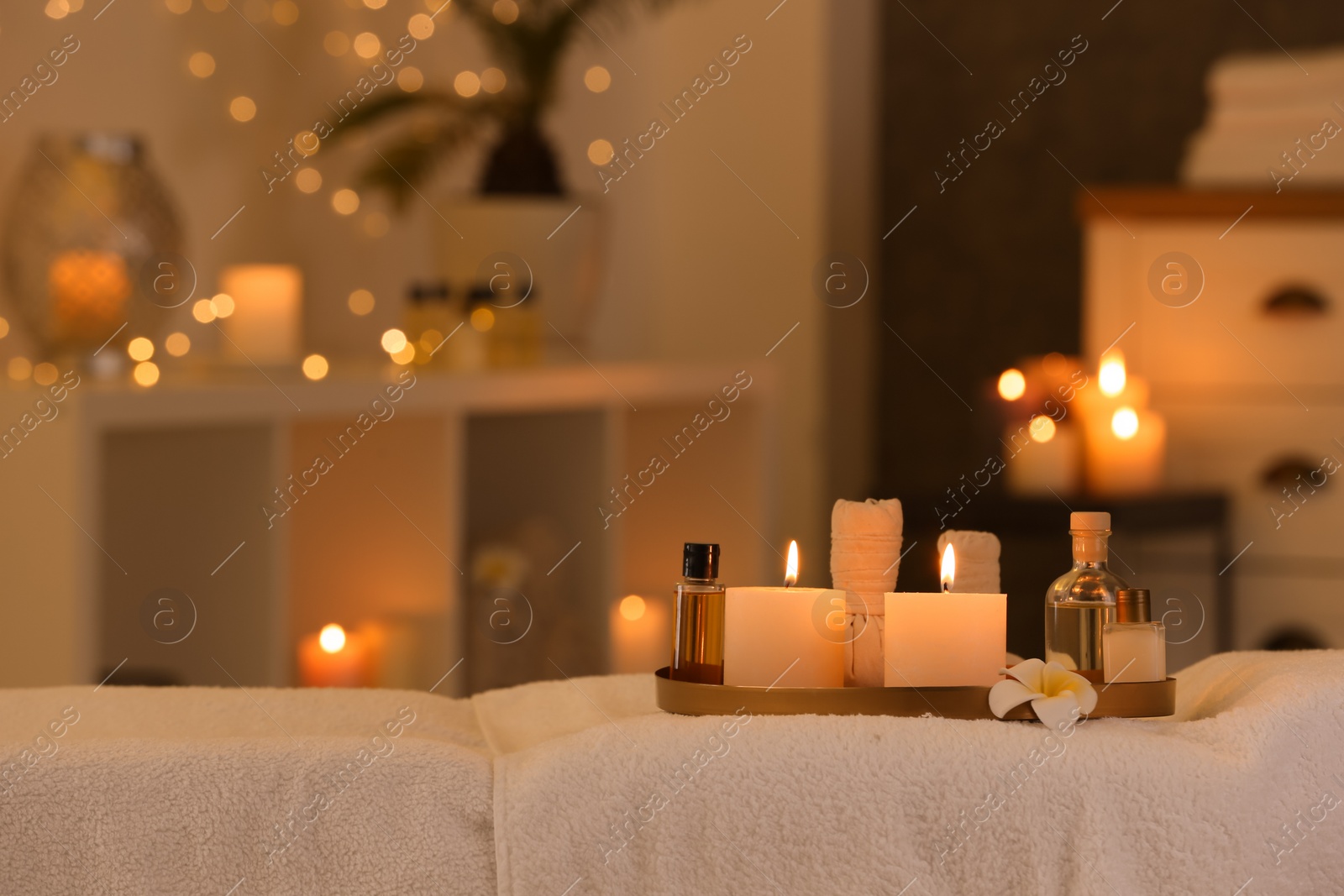 Photo of Cosmetics and burning candles on massage table in spa salon, space for text