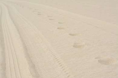 Photo of Dry beach sand with track of car as background, closeup