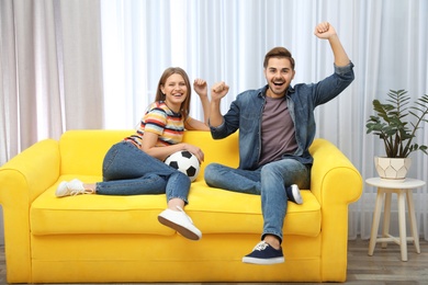Couple watching soccer match on TV in living room