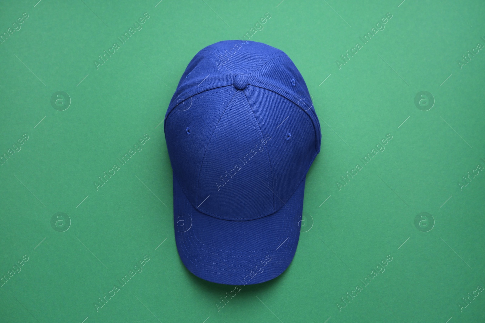 Photo of Stylish blue baseball cap on green background, top view