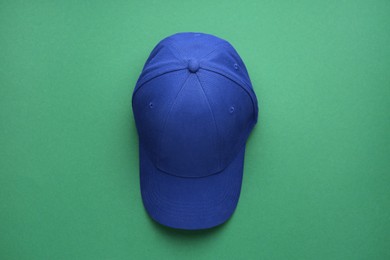 Photo of Stylish blue baseball cap on green background, top view