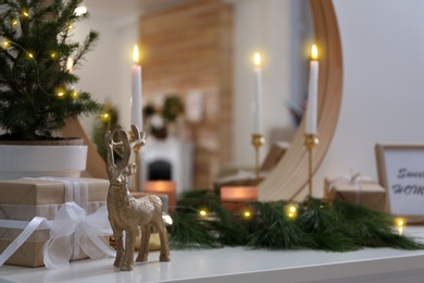 Photo of Decorative reindeer near gift box on shelf with Christmas decor. Interior design