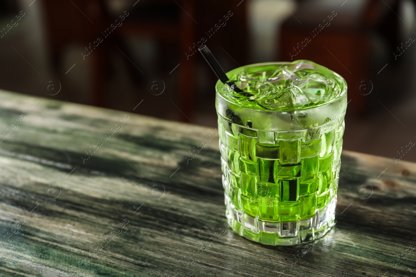 Photo of Glass of delicious cocktail with ice on table in bar