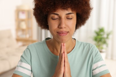 Photo of Woman with clasped hands praying to God indoors