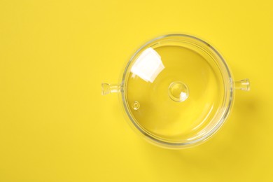 Photo of Glass pot with lid on yellow background, top view. Space for text