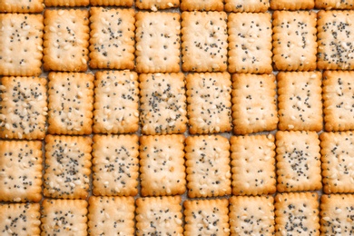 Many delicious crackers as background, top view