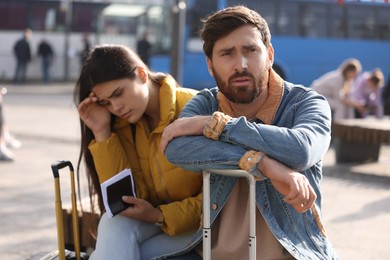 Photo of Being late. Worried couple with suitcases waiting outdoors