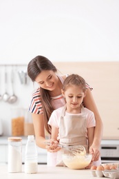 Mother and her daughter making dough at table in kitchen