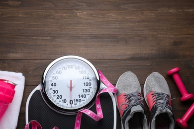 Flat lay composition with bathroom scale and measuring tape on wooden floor, space for text. Weight loss concept