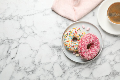 Yummy donuts with sprinkles and coffee on white marble table, flat lay. Space for text