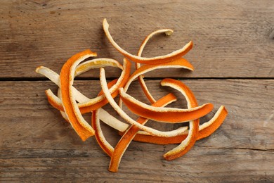 Photo of Pile of dry orange peels on wooden table, flat lay