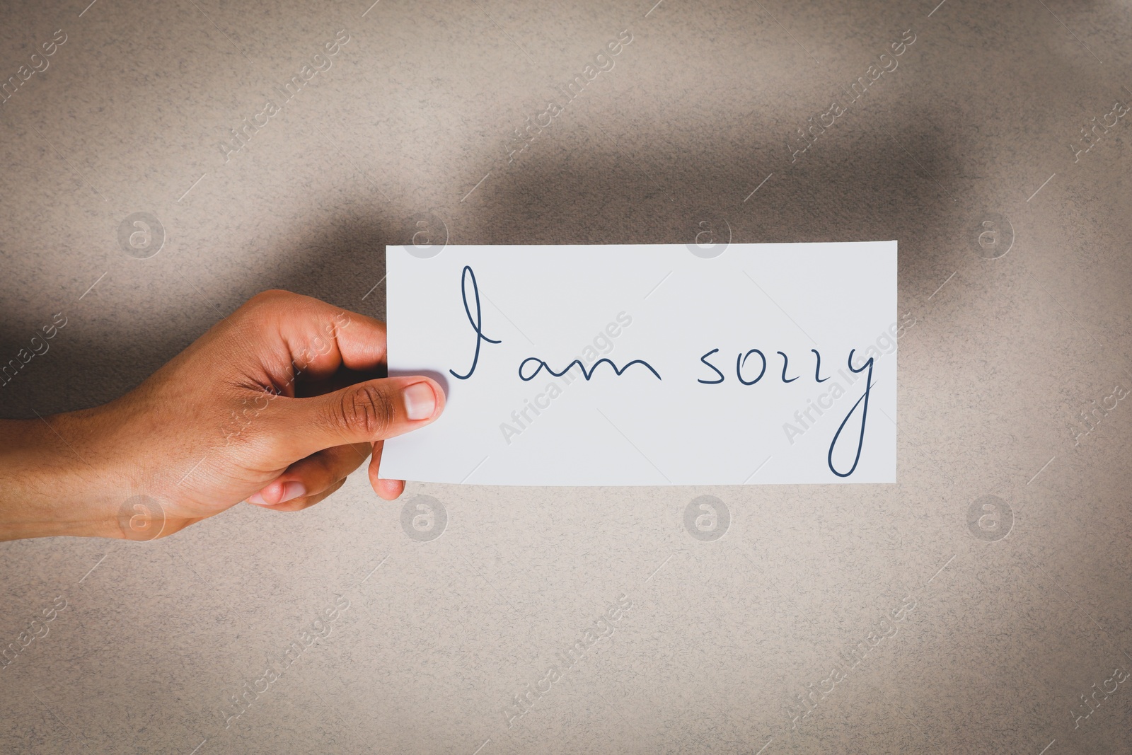 Image of Apology. Man holding card with phrase I Am Sorry on grey background