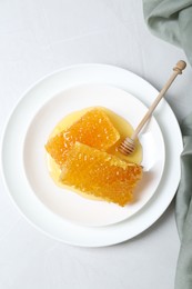 Photo of Natural honeycombs with tasty honey and dipper on white table, top view