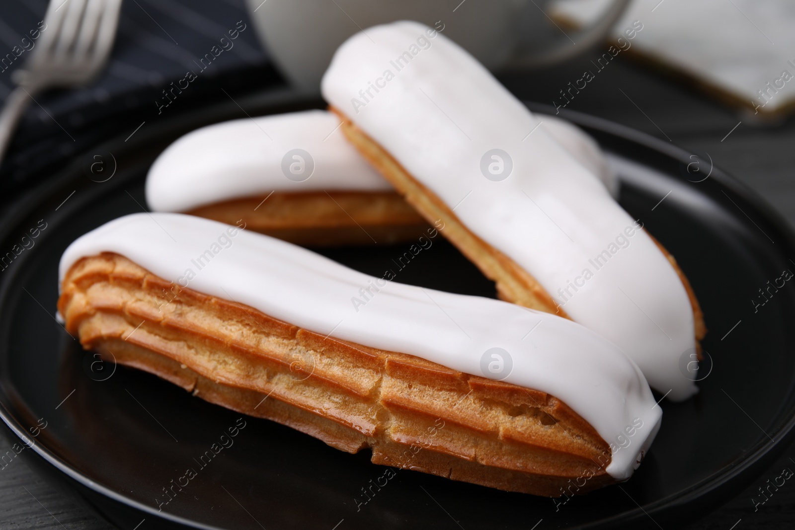 Photo of Delicious eclairs covered with glaze on table, closeup