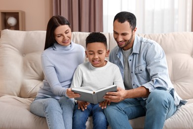 Happy international family reading book on sofa at home