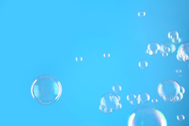 Beautiful transparent soap bubbles on light blue background