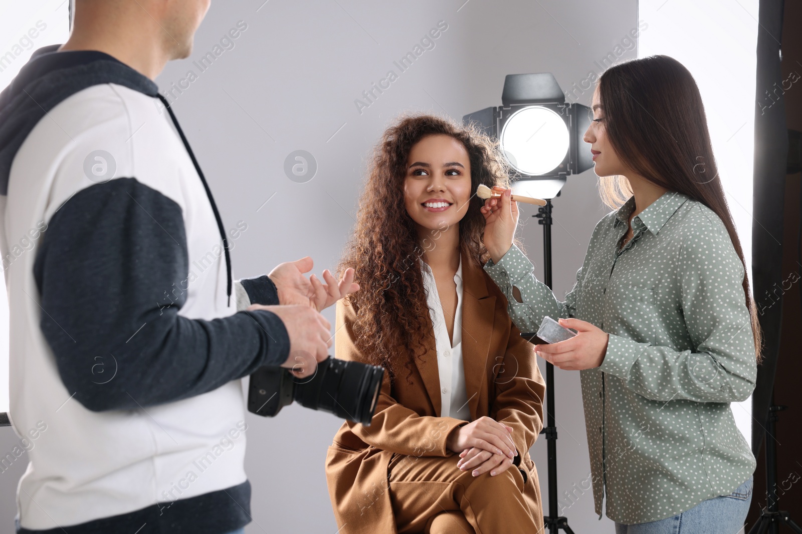 Photo of Professional photographer and makeup artist with model in studio