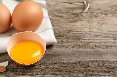 Raw chicken eggs and shell with yolk on wooden table, closeup. Space for text