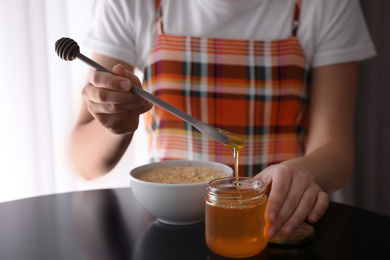 Photo of Woman with honey and spoon at black table, closeup