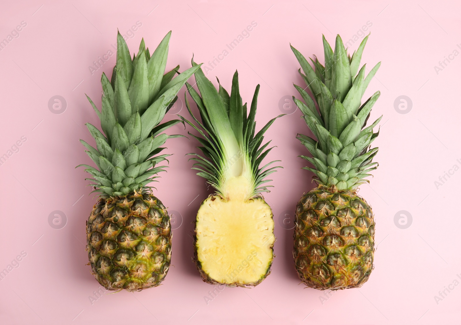 Photo of Whole and cut pineapples on pink background, flat lay