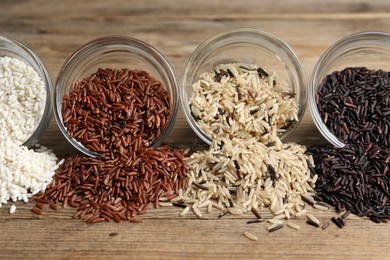 Different types of rice on wooden table, closeup