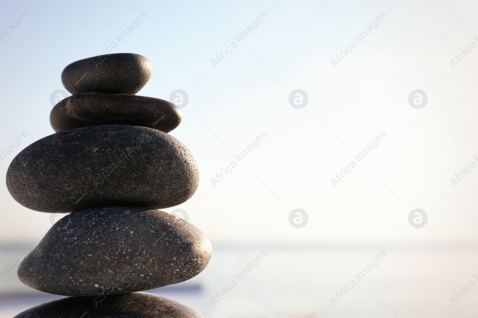 Photo of Stack of dark stones against blurred background, space for text. Zen concept