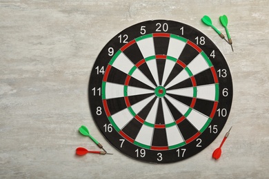 Dart board with color arrows on light stone background, top view. Space for text